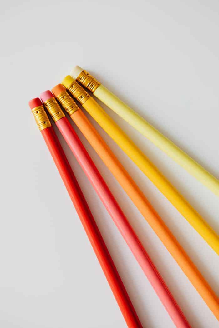 Vibrant red, orange, and yellow pencils aligned on a white surface.