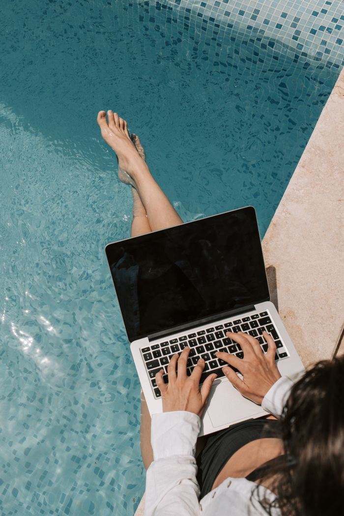 services-img Woman working remotely on a laptop by the poolside, enjoying summer outdoors.
